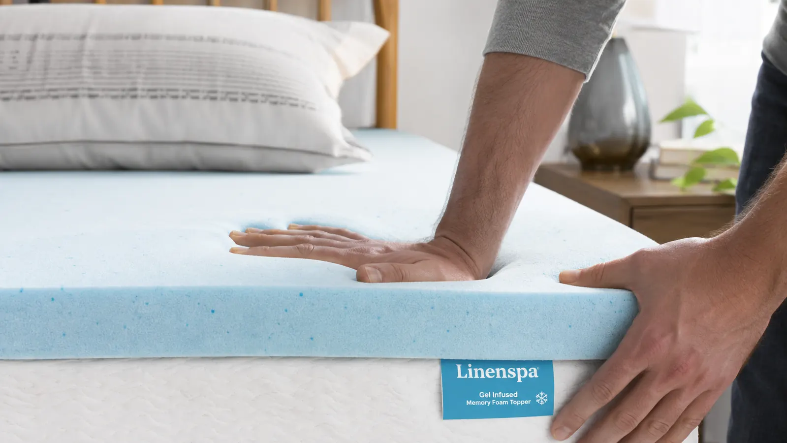 Close-up of a hand pressing into the Linenspa gel memory foam topper showing the slow recovery of the foam
