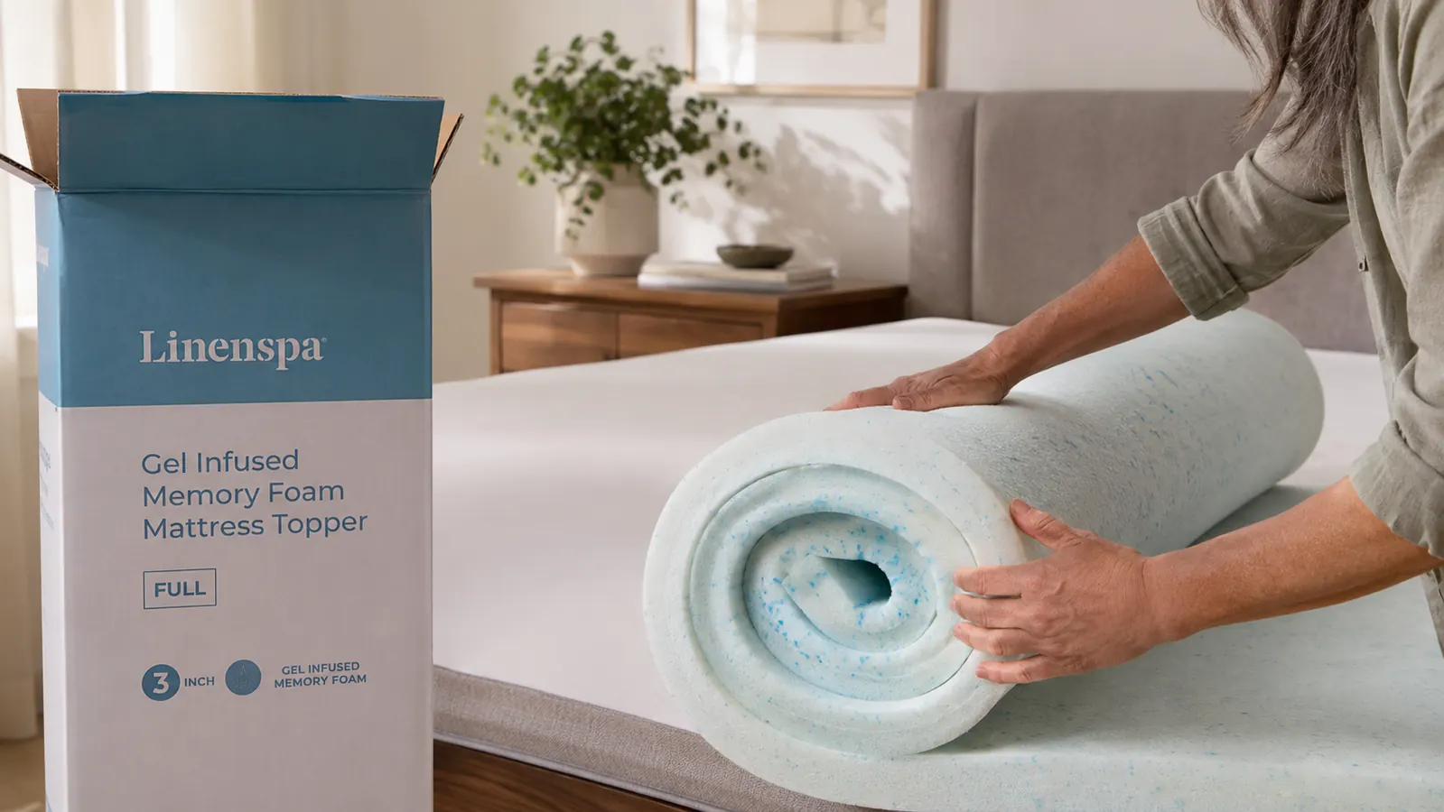 Unrolling a Linenspa gel memory foam mattress topper onto a bare mattress before making the bed